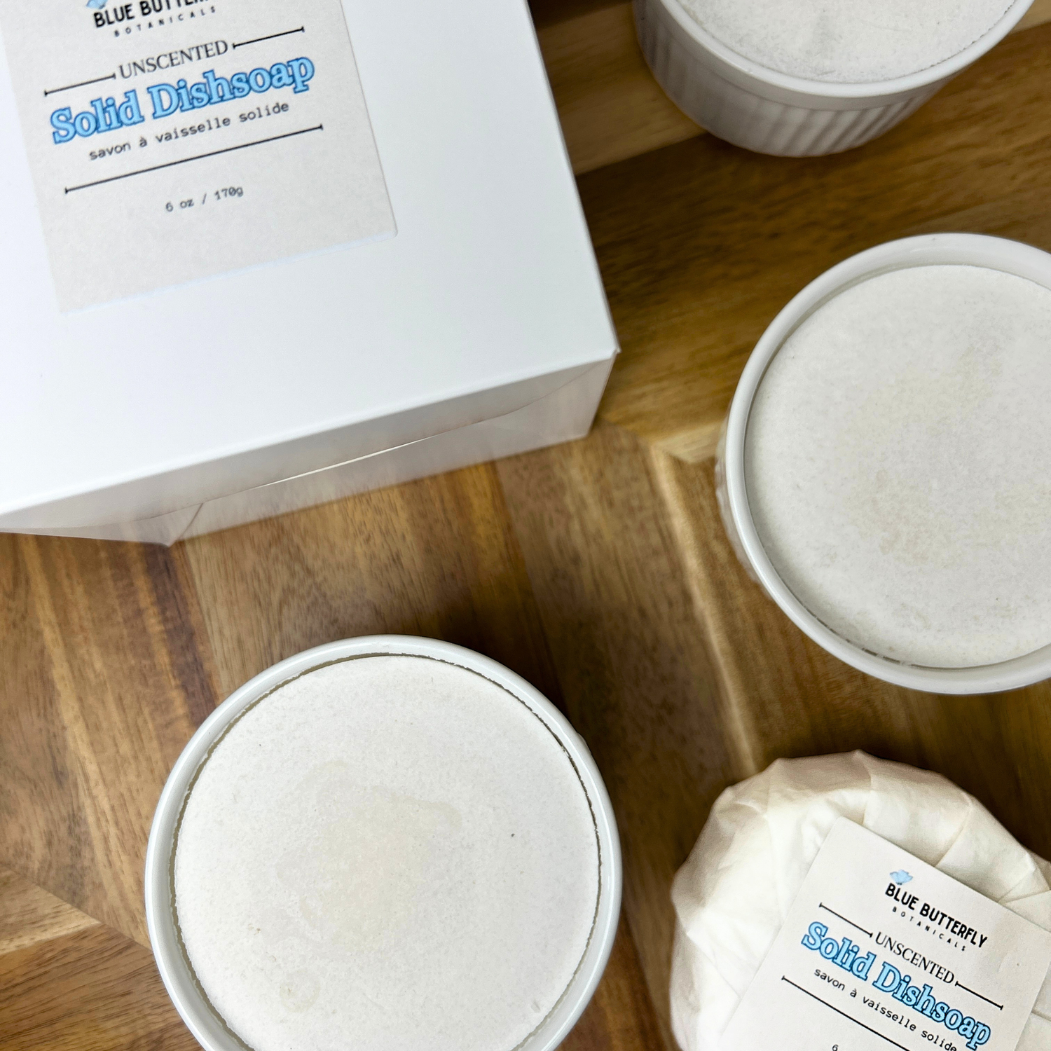 Solid dish soap bars on a wooden surface with packaging.